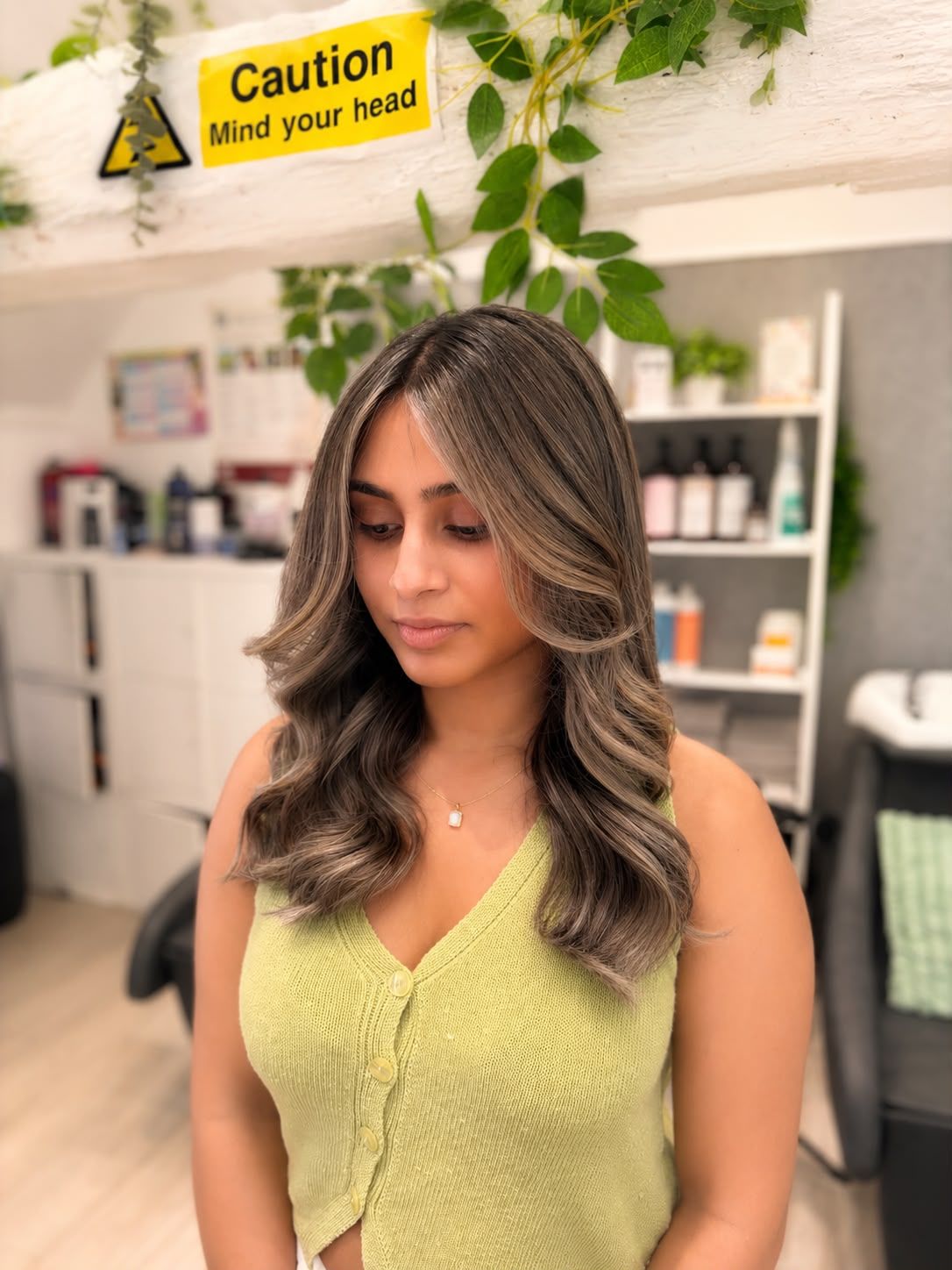 Long brunette hair with soft blonde face-framing highlights, styled in loose waves